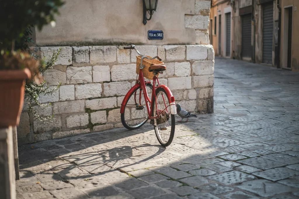 A red bicycle standing in a cobblestone plaza, the input image for Ideogram's object removal example, as shown on Object Remover