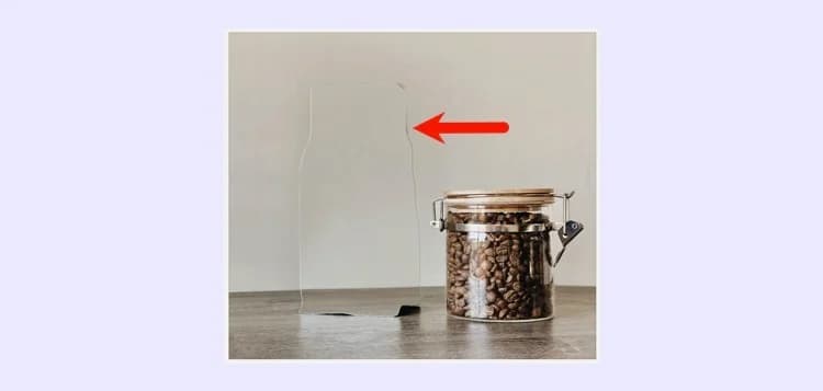 A faint bottle-shaped outline left behind after a Photoroom Retouch pass, marked with a red arrow, next to an intact jar of coffee beans, as taken from Photoroom