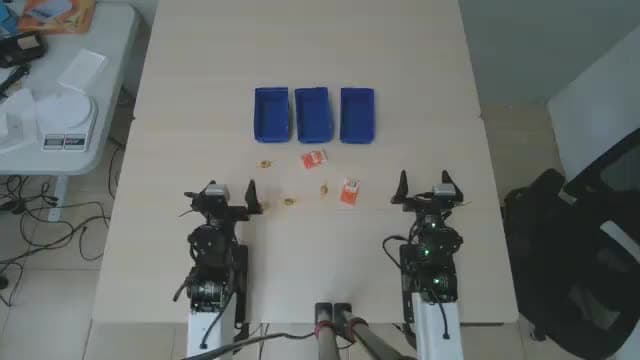 Un robot de dos brazos en el sitio de la beta de Anvil Robotics clasificando objetos pequeños hacia tres bandejas azules, según Dream Labs